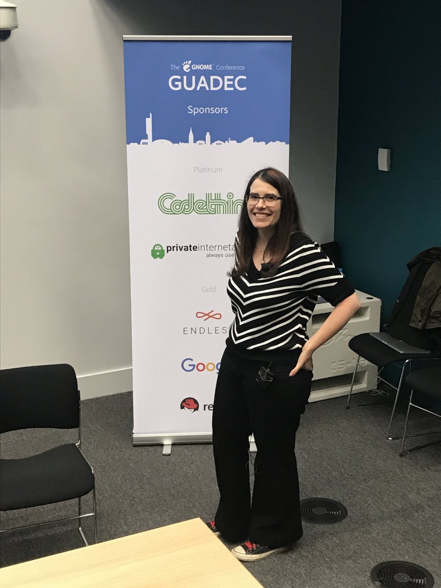 Photo of Karen in front of a banner at GUADEC