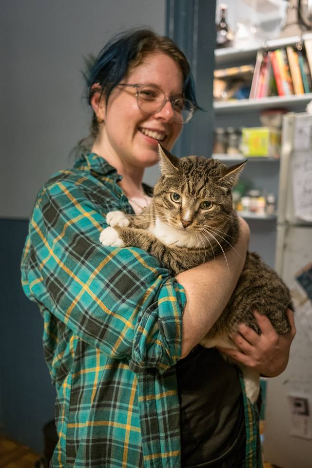Molly de Blanc, a blue-haired woman holding a brown tabby cat