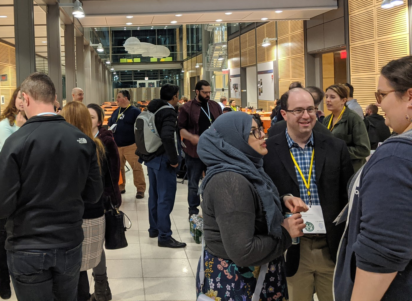 A cluster of three people conversing in the foreground, with others in the background, at a reception