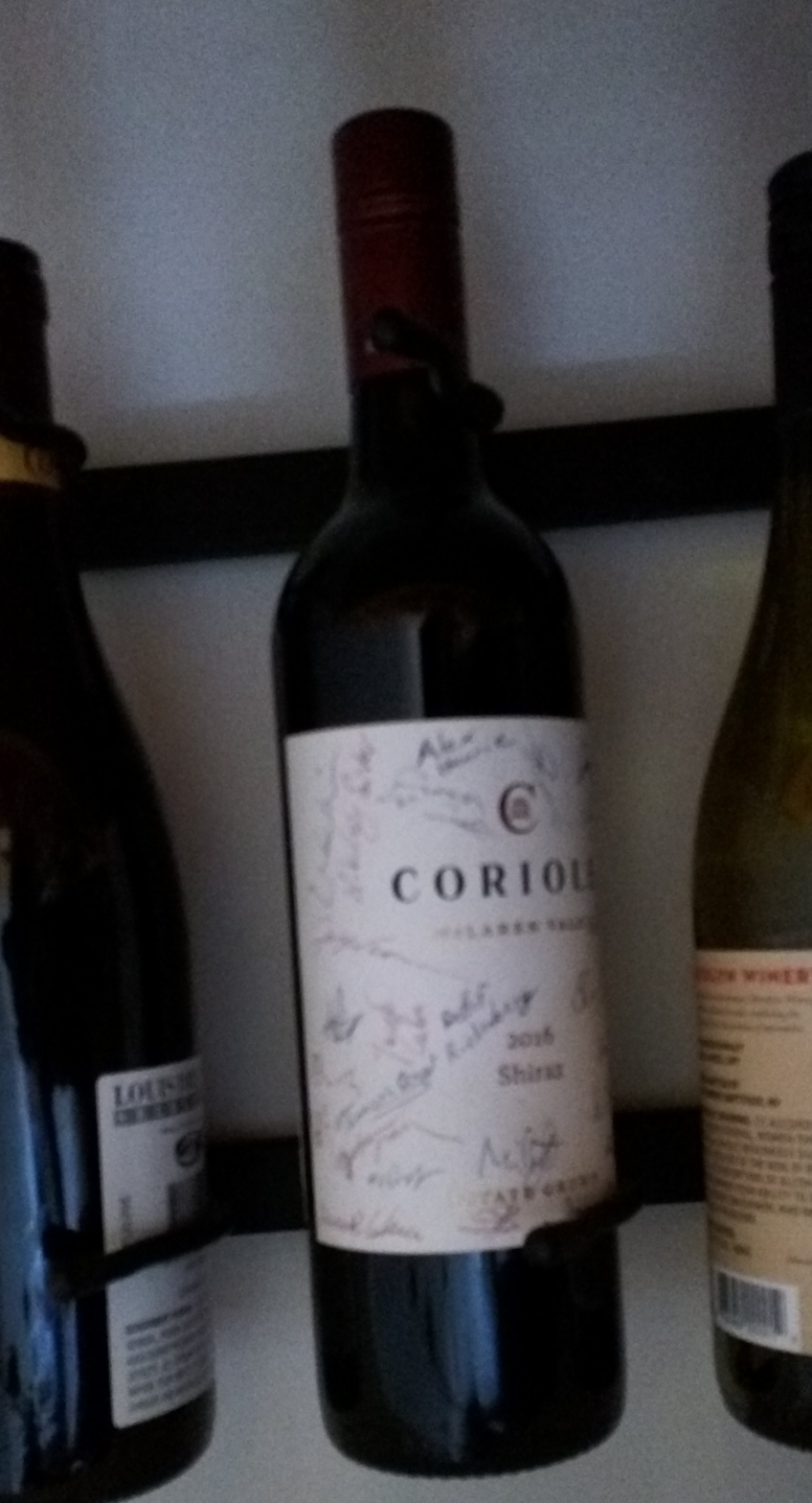 Slightly fuzzy picture of a wine bottle with signatures on it
