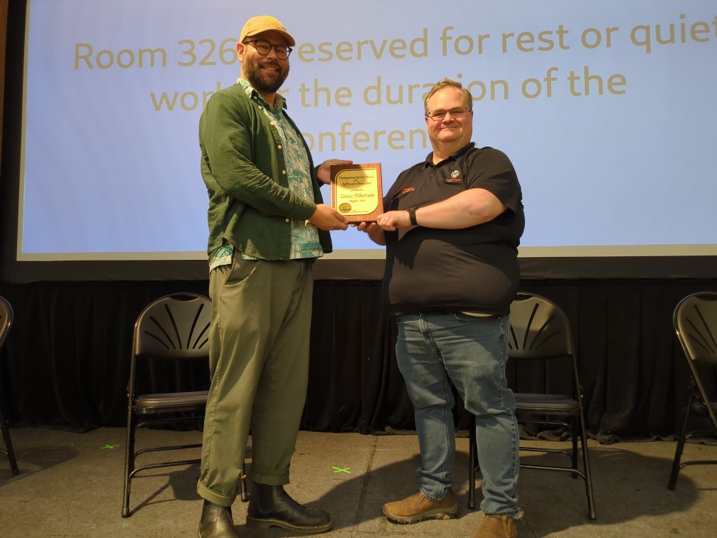 Picture of Pono giving Lance an award on stage at FOSSY